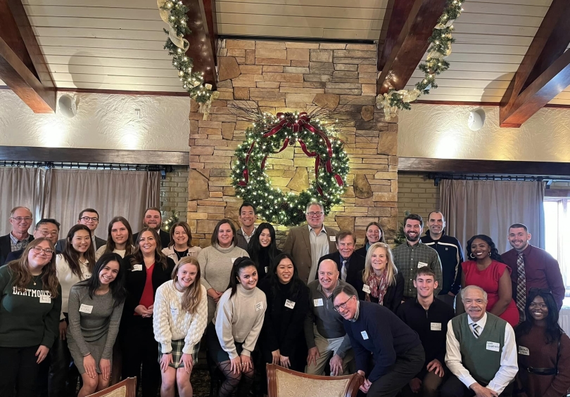 A photo of me, Lauren, along with those that attended the luncheon. We are standing in front of a fireplace and wearing business casual clothing.