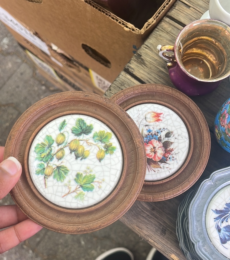 An image of a wooden coaster with a porcelain middle, among other items on a table.