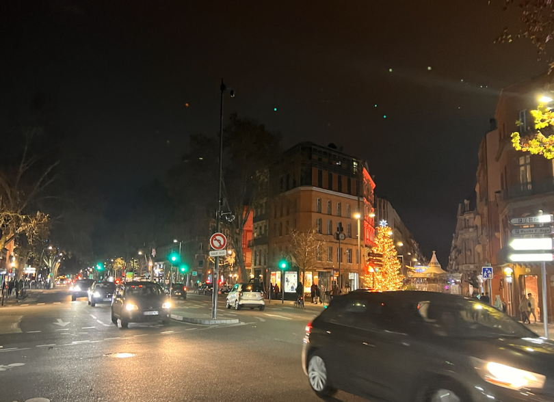 Two cars passing by at night in Toulouse accompanied by street lights