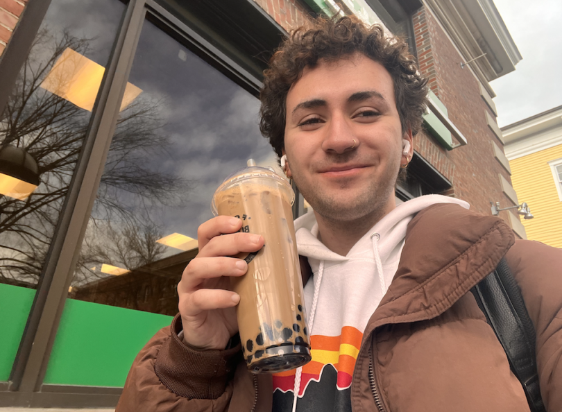 Blogger smiling, holding their boba drink (light brown tea and dark brown tapioca pearls inside)