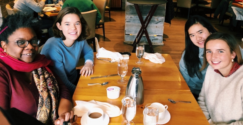 Taking my professor out to Pine! Abbi and 2 friends with Professor Francis sitting around a restaurant table.