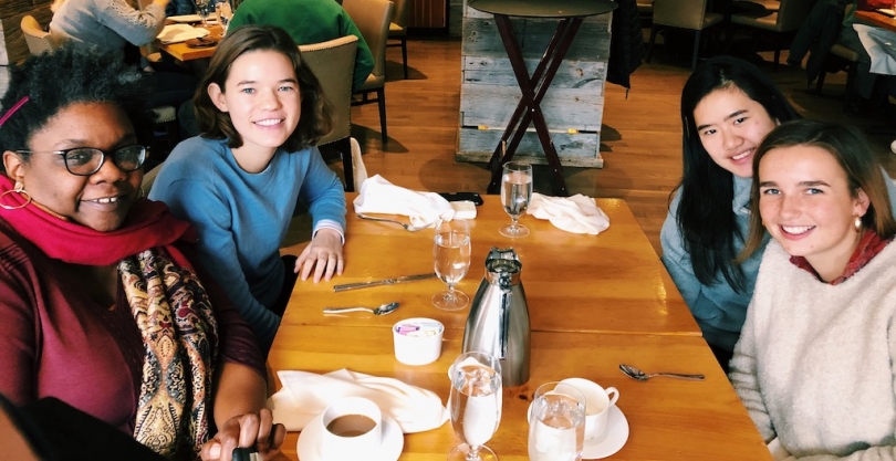 Abbi and 2 friends with Professor Francis sitting around a restaurant table.