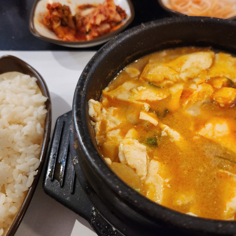 Sundubu-jjigae, rice, and side dishes on a table 