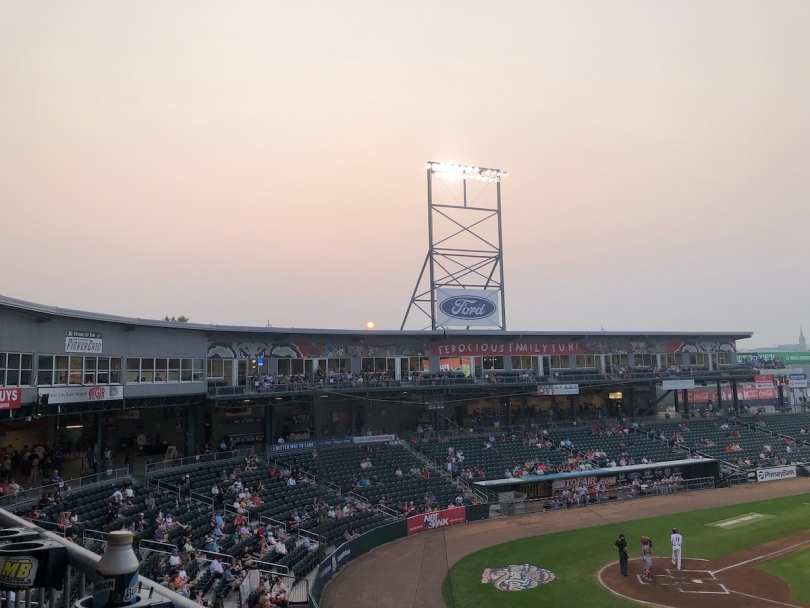 The sun sets behind a baseball stadium