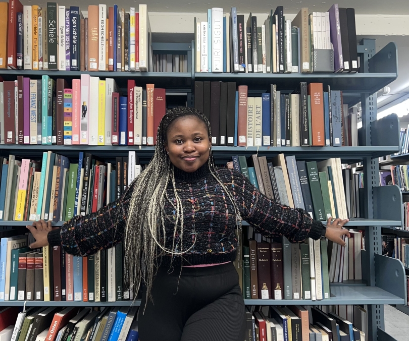 Shandu poses in front of a wall of books by the Sherman Stacks.