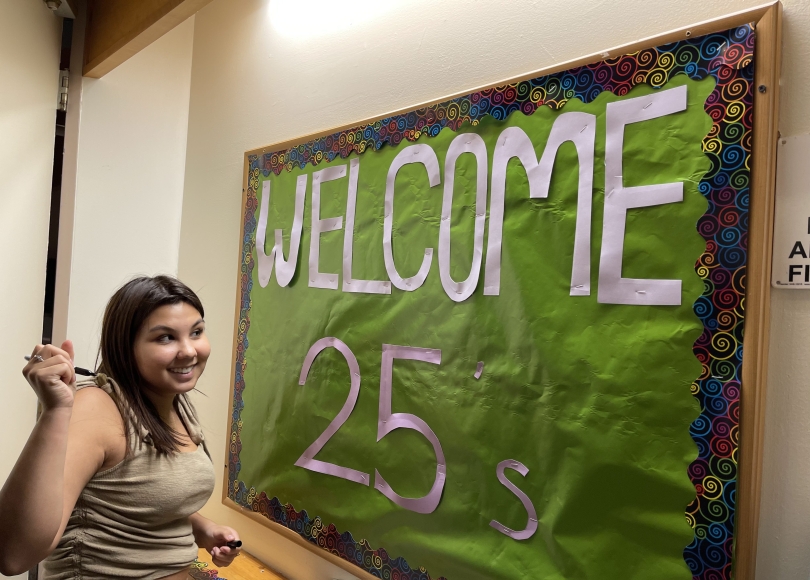 A '25 signs the French Hall welcome board during Move-In Weekend in 2021.