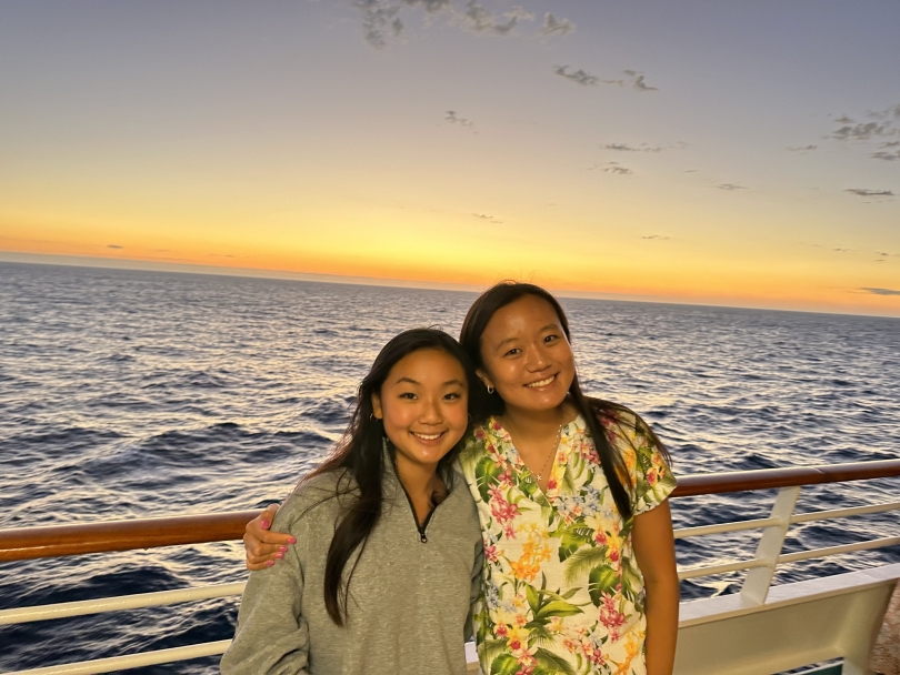 My sister and I smile for an ocean view sunset shot on a cruise ship.