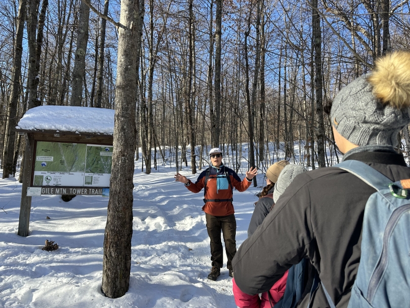 Our trip leader gives a short talk in front of the Gile Mtn. Tower Trail before we hike up the snow-covered trail