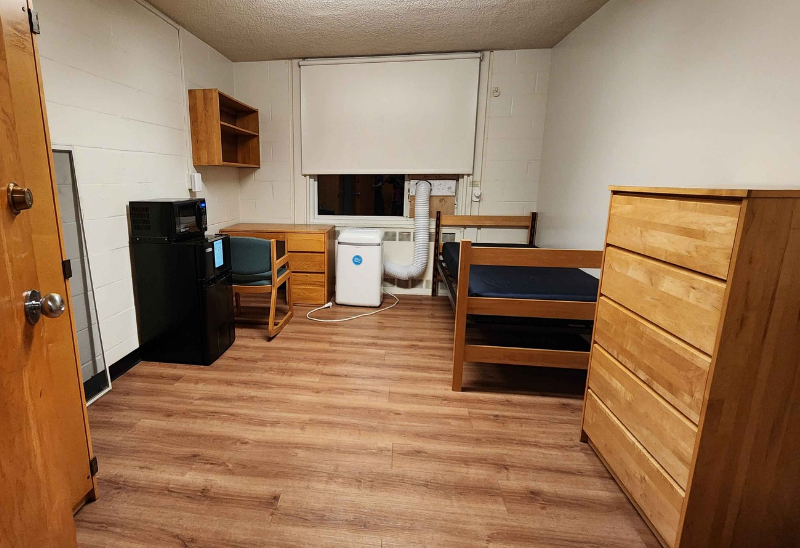 A picture of a first-year dorm room in Little Hall with wooden floors and basic College-provided furnishings.