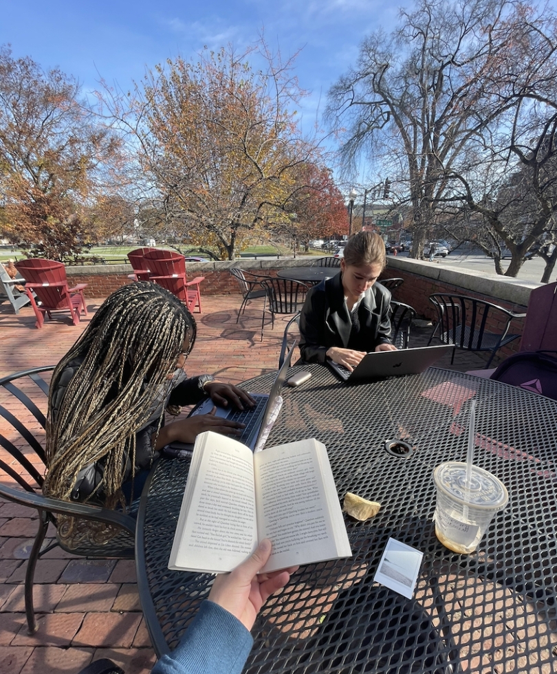 two Dartmouth students on the porch of the student center building, sitting, reading and doing work