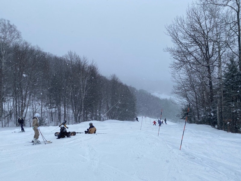 A picture of a few people laying on the main slope of the Dartmouth Skiway, as snow falls onto the trail