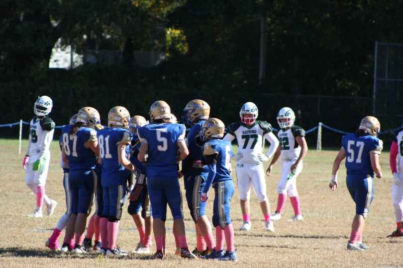A group photo of the team planning their next move while some members of the opposing team look on.