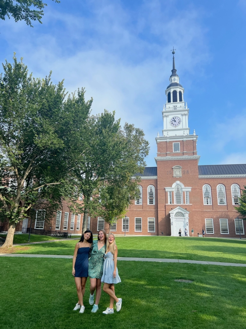 three girls smiling in front of Baker tower lawn