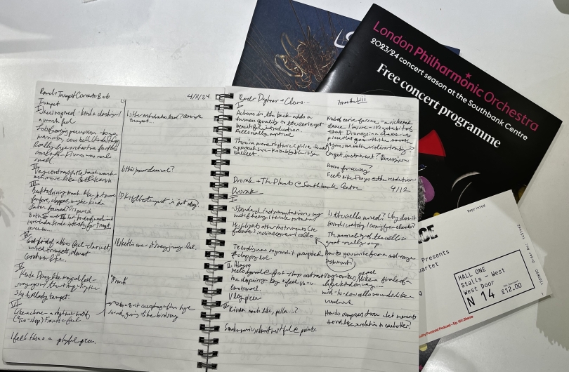 An image of a notebook with notes written on it about music performances in front of some concert programs