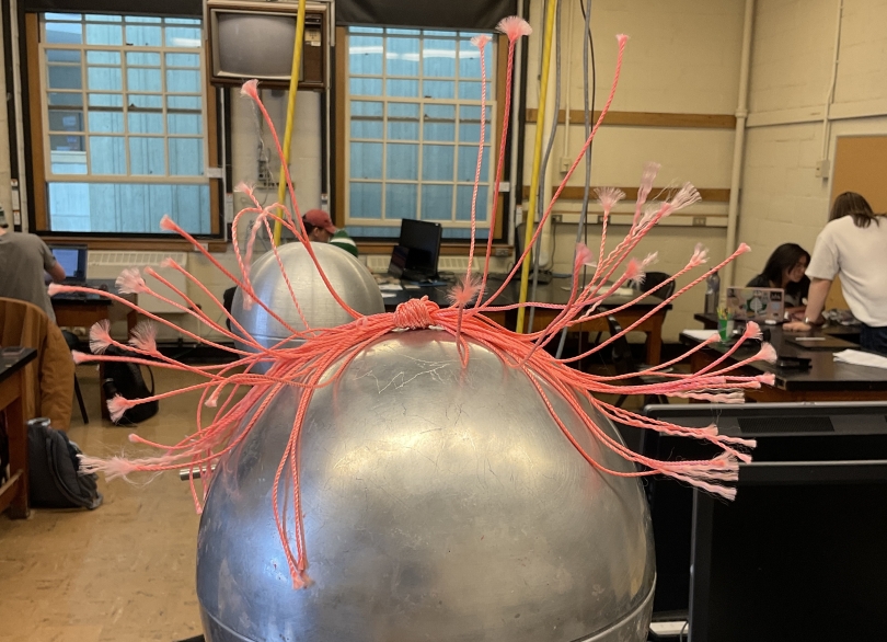 a picture of a van-de-graaff generator and strings raining away from it due to accumulation of charge