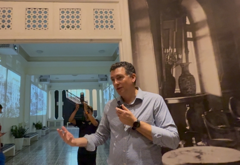 Professor Miller speaking into a microphone at the Independence Palace