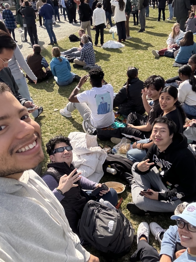 Students sitting on the Green enjoying the eclipse