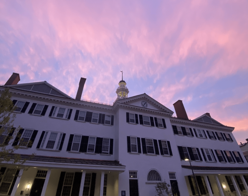 a view of the back of Dartmouth Hall with a purple sunset seen in the sky above it