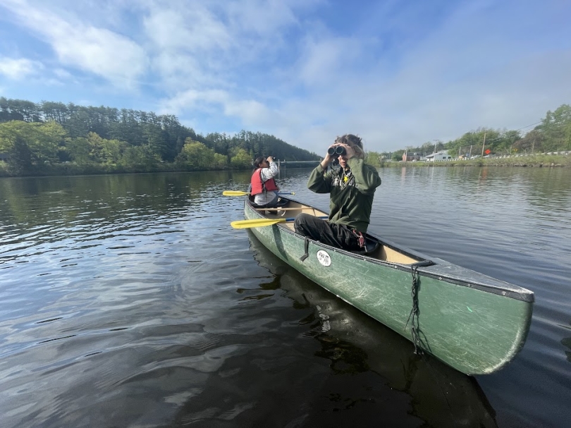 a picture of ada in a canoe, looking through some binoculars