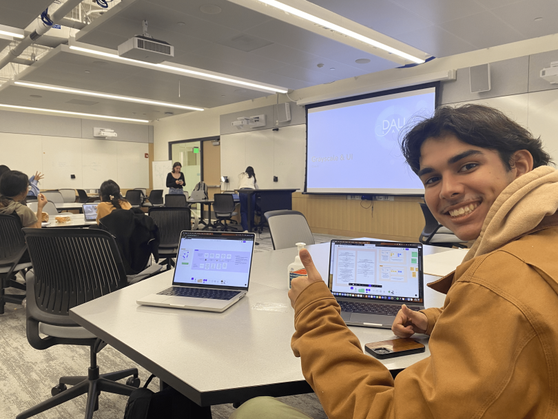 martin's roomnmate zach giving the thumbs up in their DALI design class as he works on something on his laptop