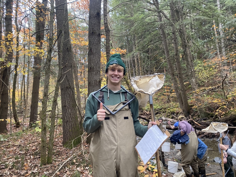 a picture of martin holding his net and clipboard in front of the stream
