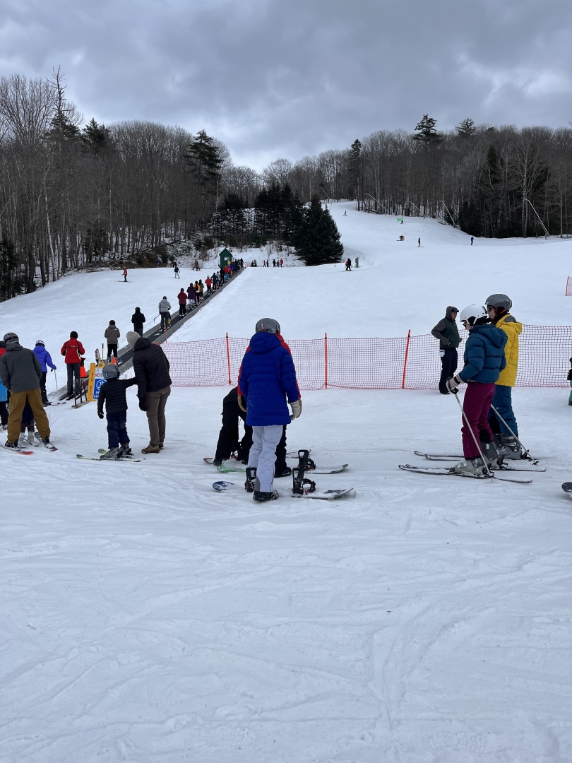 Skiers and snowboarders waiting at the base of the Magic Carpet at the Dartmouth Skiway