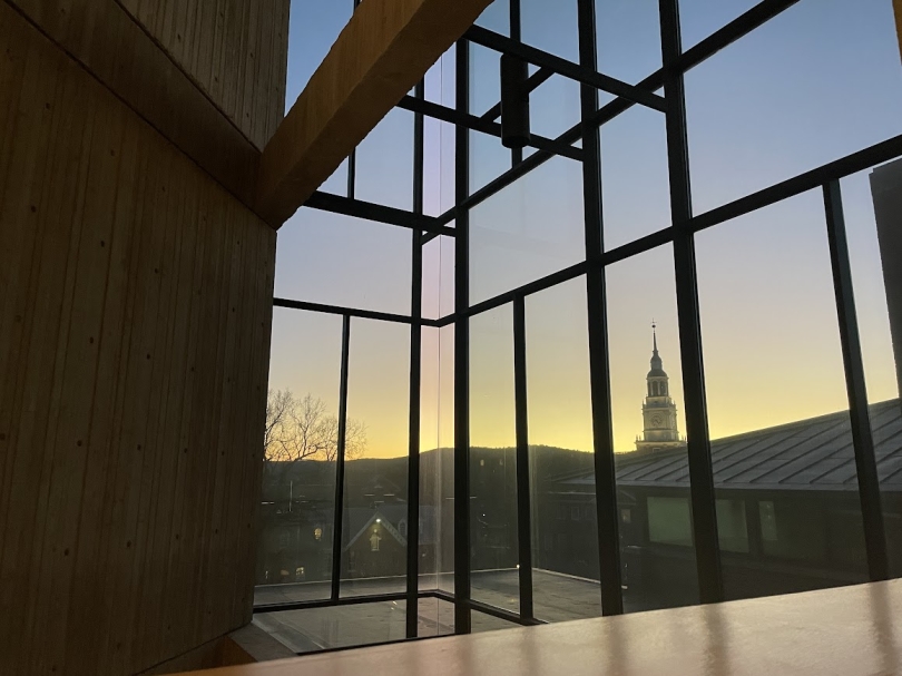 a picture of Baker Tower seen through the windows of Fairchild fourth floor when the sun has set and the sky is a mix of yellow, purple and blue