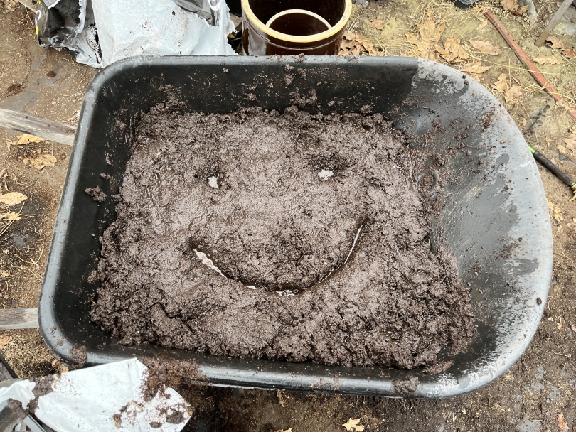 A wheelbarrow full of freshly made potting mix. A smiley face has been drawn in the top of the soil