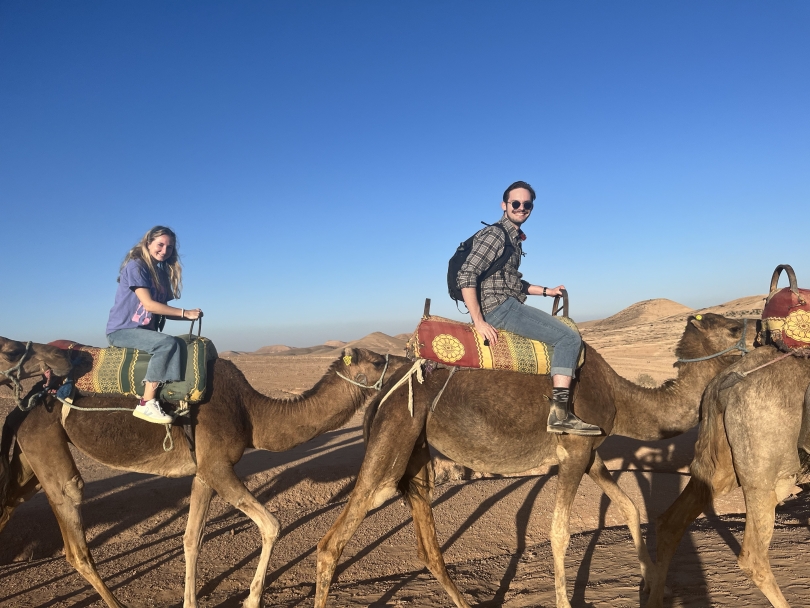 2 people on camels in a desert
