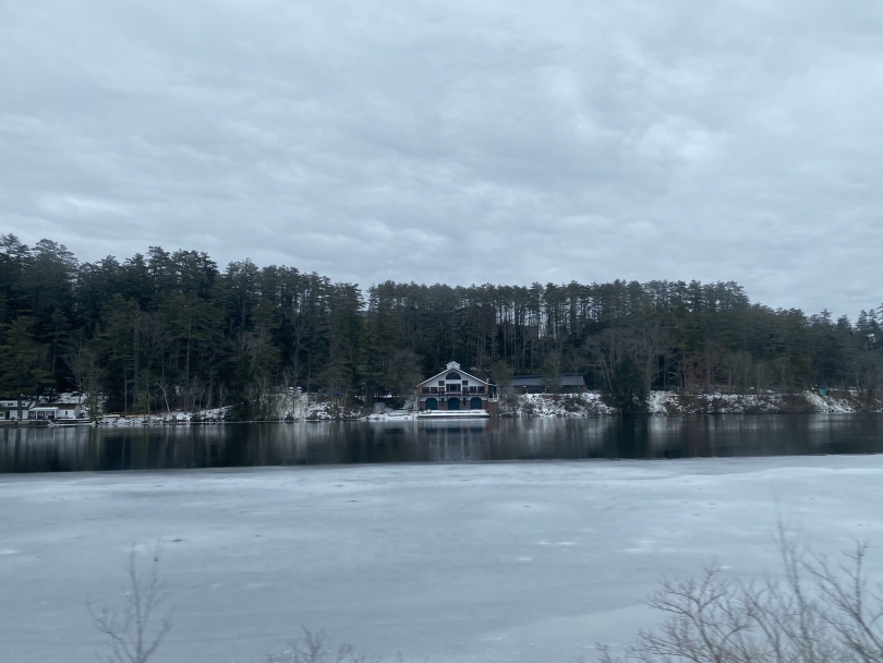 a picture from across the river of the dartmouth rowing facility, with the ice beginning to melt