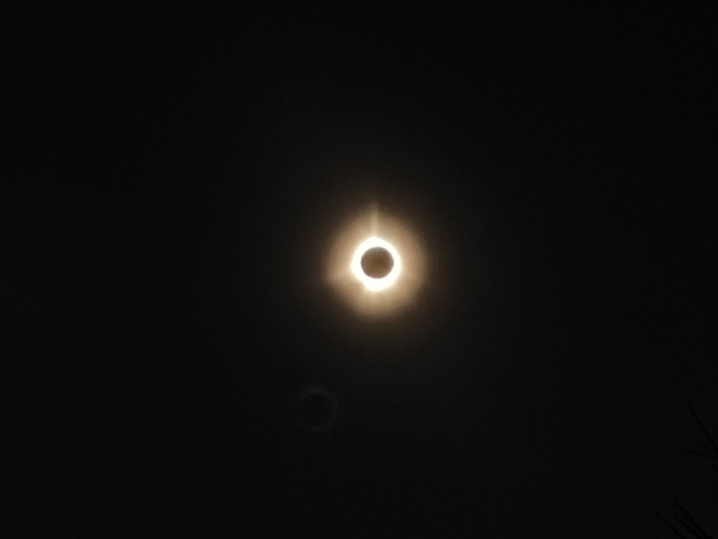 an orange ring of light surrounding the moon, as it glows with an etheral glow during a total solar eclipse