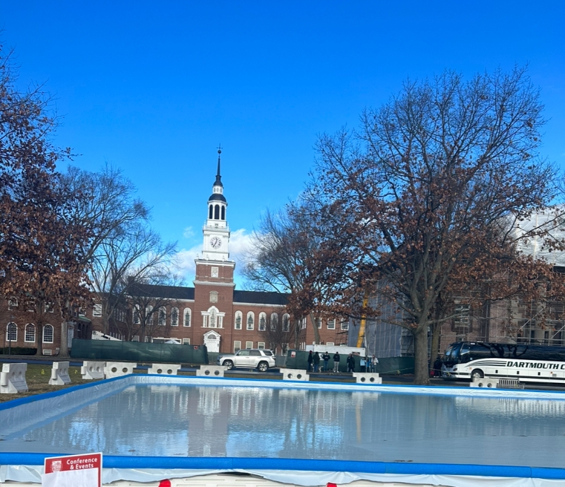 A bright blue sky ensconces the view of the brown and white Baker-Berry library, sandwiched between an ice skating rink in the periphery.
