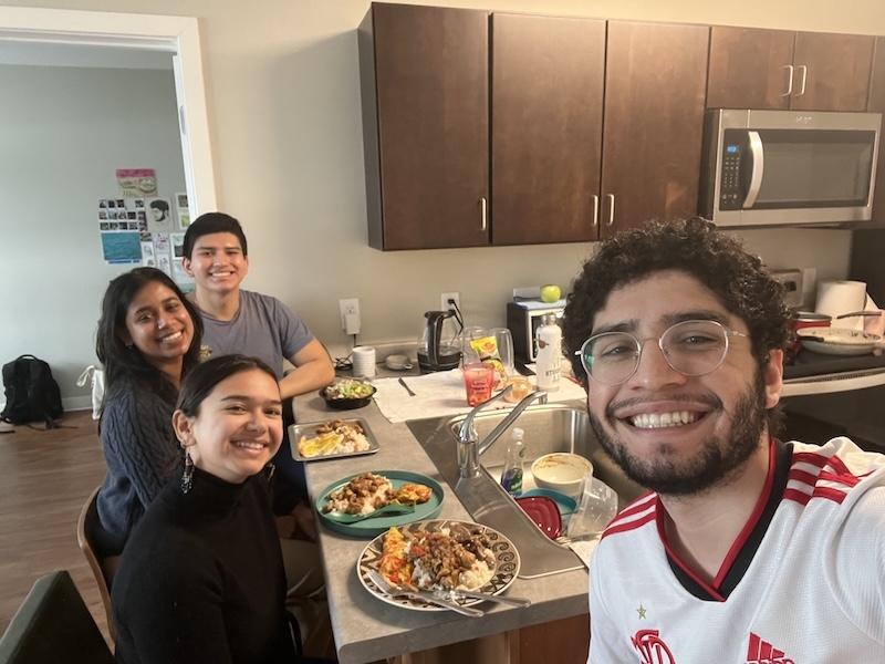 An image of four students in an apartment having a meal