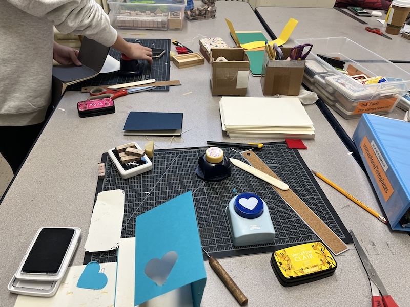 An image of a journal being made on a table with rulers, mats and art materials