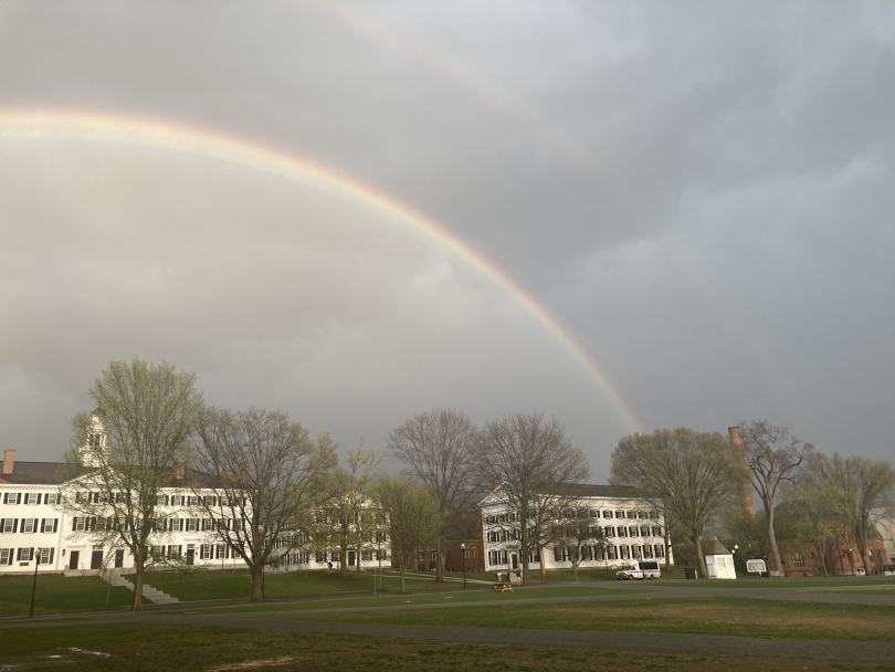 a view of a rainbow on a cloudy day above Dartmouth Hall and trees