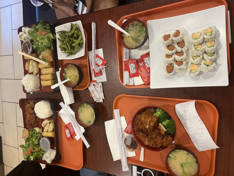 An image of a table with sushi, bento boxes and rice bowls