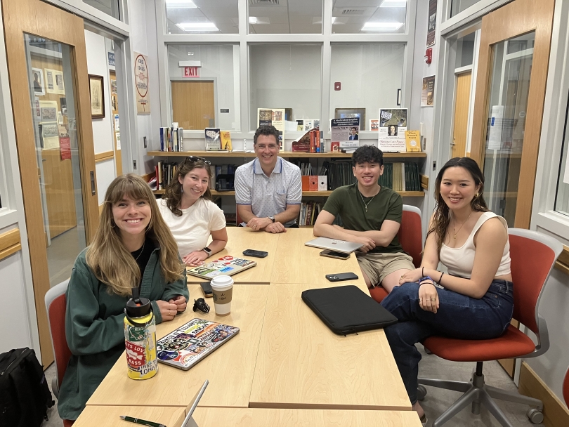 5 people smiling at the camera while sitting down
