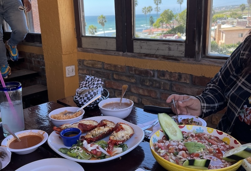 An image of seafood on a table with a background of a beach visible through a window