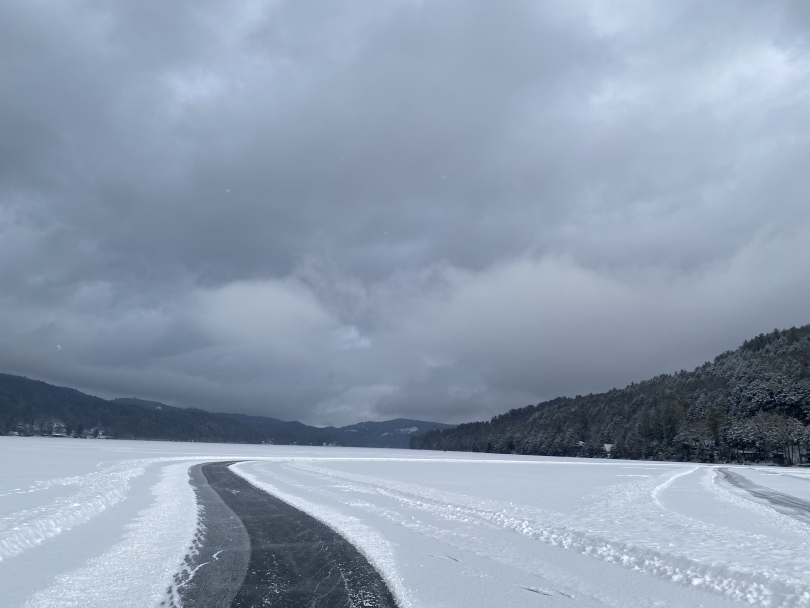 A landscape view of frozen Lake Morey covered in snow with a skating path cleared in the center. 