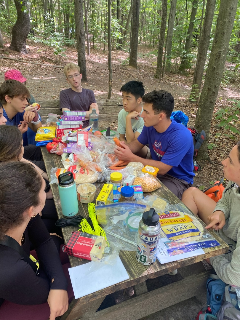 martin and his trippees around a table discussing classes, dartmouth, and more as they eat a snack