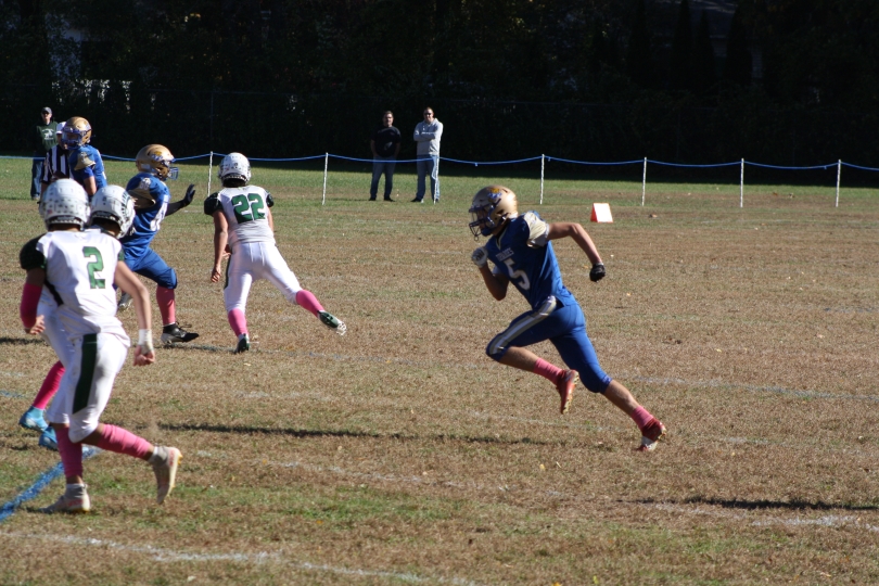 A photo of my brother running with awesome form to get into the foray of whatever particular football play was happening in that moment. He is positioned front and center and is the clear focus.