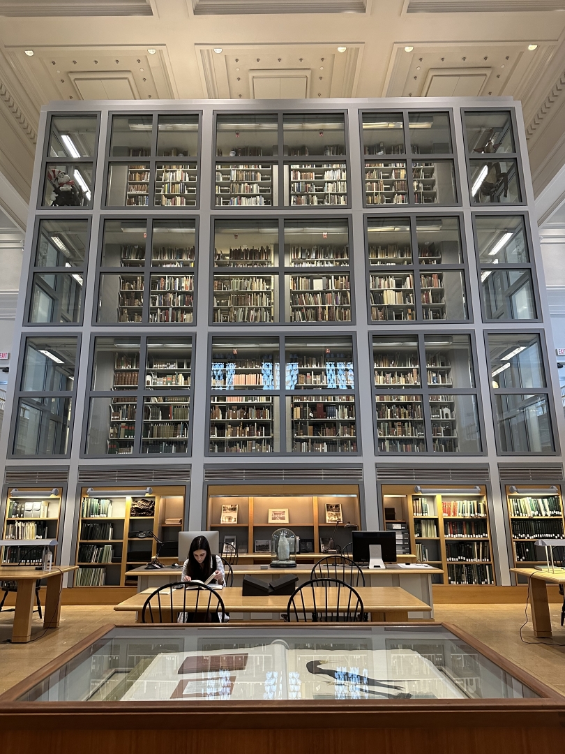 A stack of books line up towards the ceiling behind an enclosed glass case in the Rauner library.
