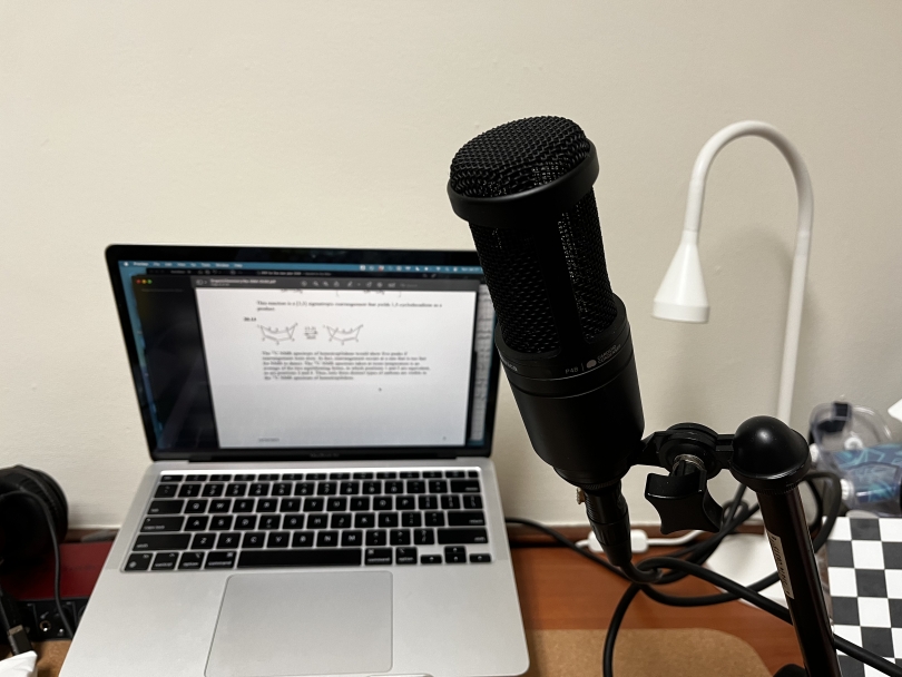 A picture of a black recording microphone in front of a laptop 