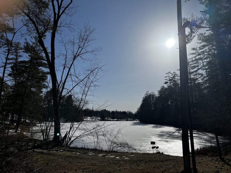 An image of Occom Pond frozen over but with the sun