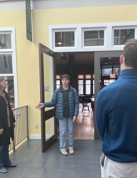 A photo taken in Collis Student Center of a tour guide wearing a backpack. The tour guide appears to be talking, with their back facing Collis Common Ground.
