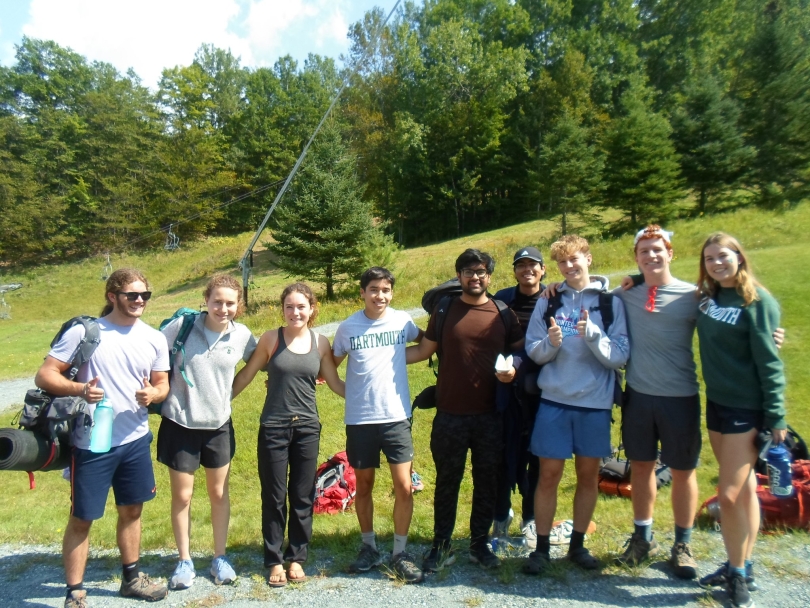 a photo of martin and his first trippees, when he was on his first-year trip, all smiling and waving as they get ready to get on the bus and head back to Dartmouth