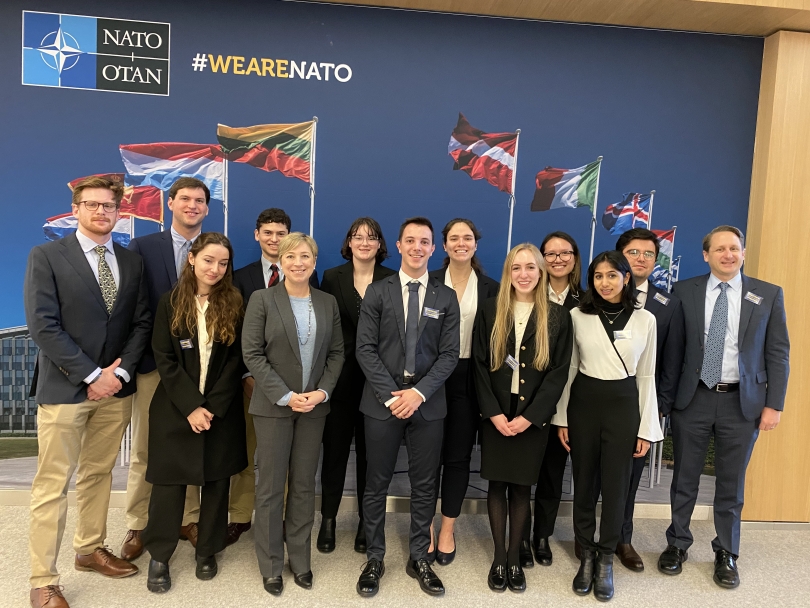 War and Peace fellows standing in front of NATO poster
