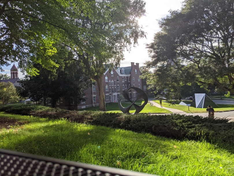 View from a park bench outside a lecture hall overlooking green scenery just before sunset