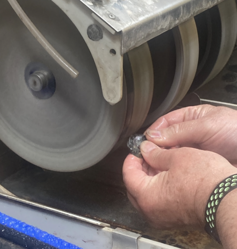 Jeff, the Jewelry Studio instructor, takes the stone bead to the abrasive wheels to demonstrate how to shape it.