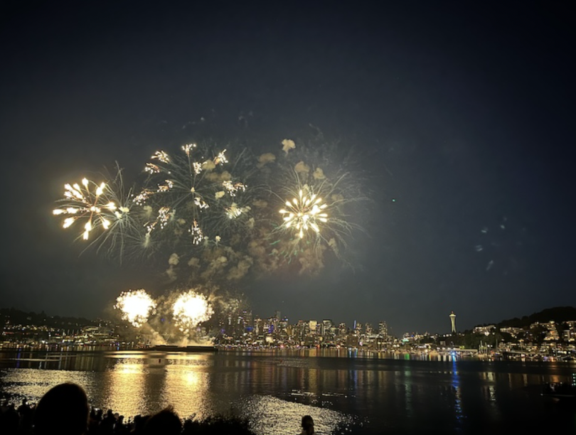 An image of fireworks over the water, across the skyline of Seattle